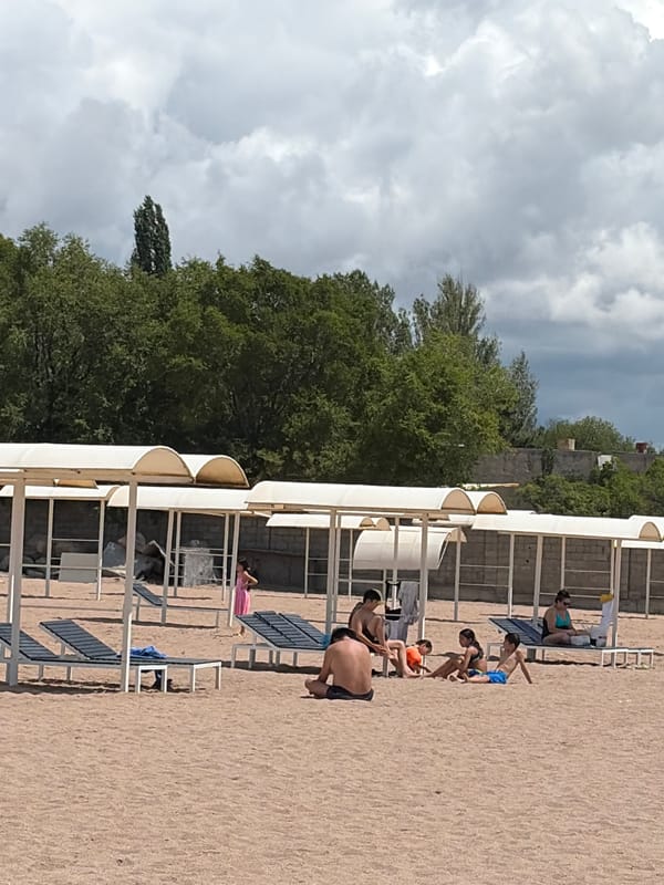 Relaxed beach day at a pier with calm water and canopies