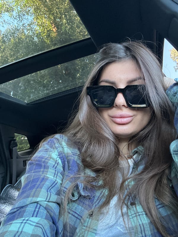 Woman in sunglasses rests in car, gazes at sunroof