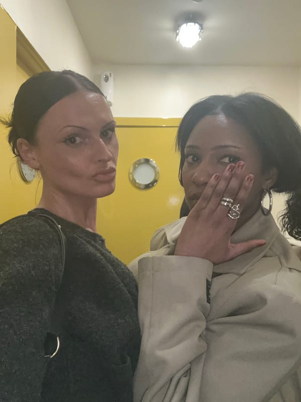 Two women photographed against yellow wall in London