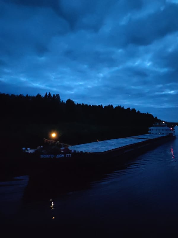 Cargo barge navigates Russian waterway near Старое Петровское at night