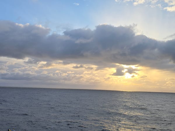 Ocean sunset observed under cloudy skies with warm reflections