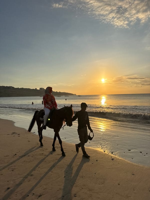 Beach sunset scene captures walker and horseback rider in Kuta