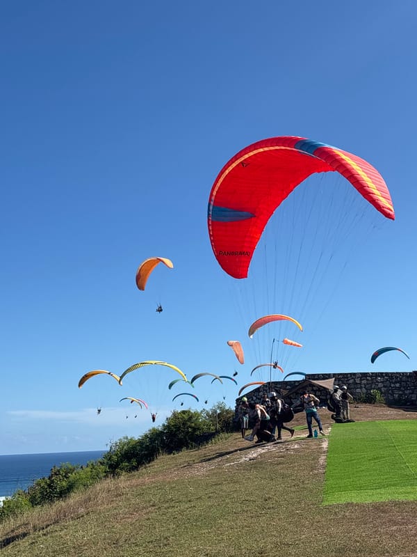 Colorful paragliders soar above Kuta Selatan coastline during morning session