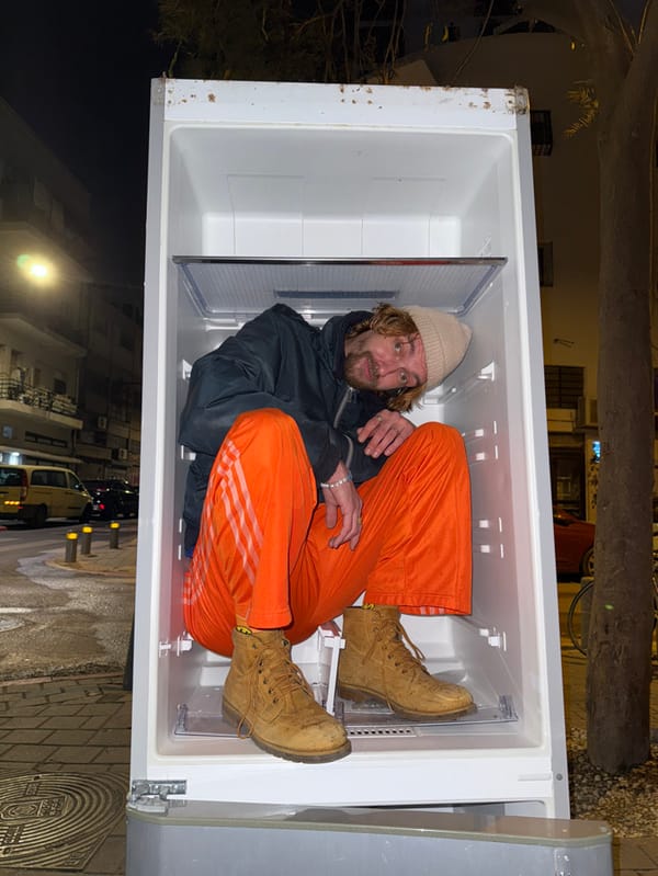 Person sits in outdoor refrigerator on Tel Aviv street
