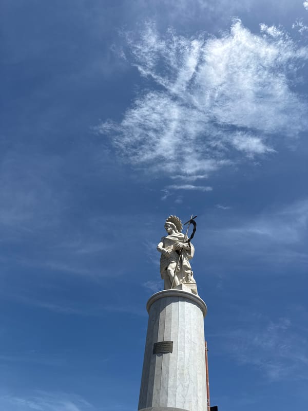 Coastal statue and breakwater documented in seaside urban area