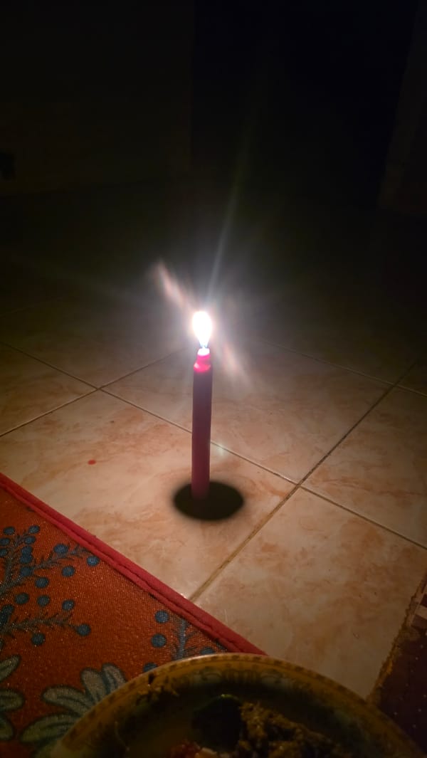 Red candle burns on tiled floor in Lhokseumawe