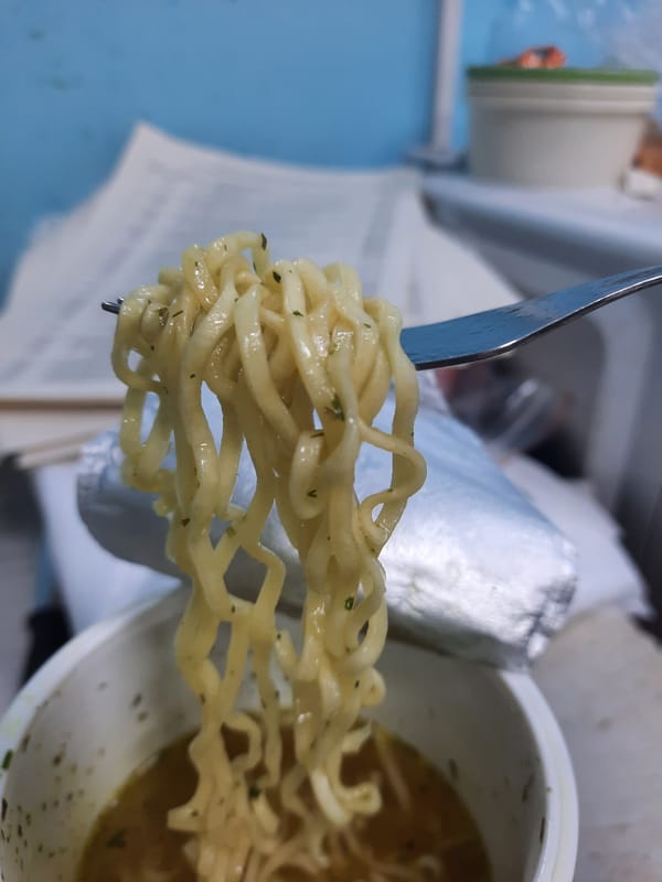 Person eats noodles in cluttered Krasnogorskoye storage area