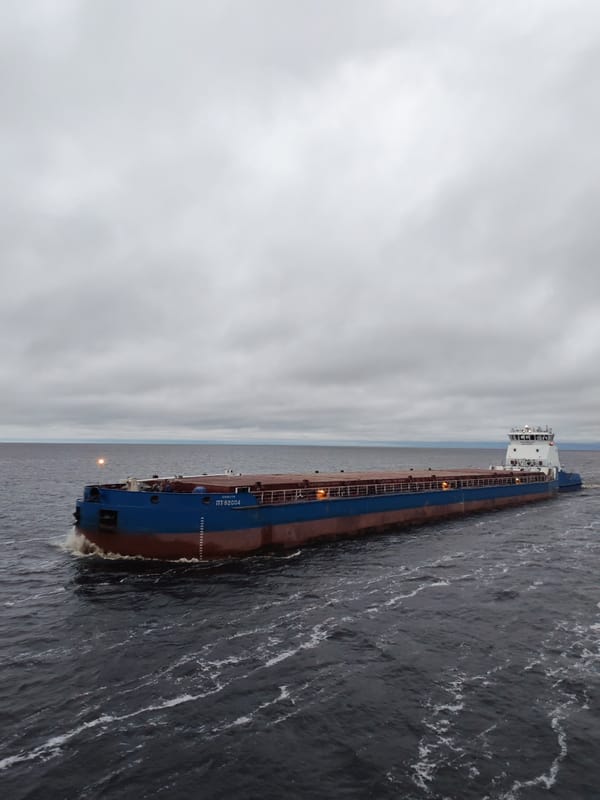 Tugboat pushes barge through choppy waters near Bereg, Russia