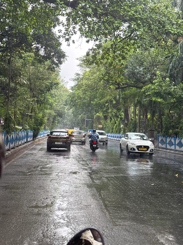 Motorcyclist navigates wet Kolkata streets during morning rain