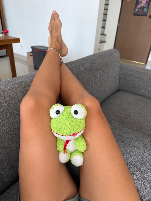 Person relaxes with plush frog toy in Kuta Selatan