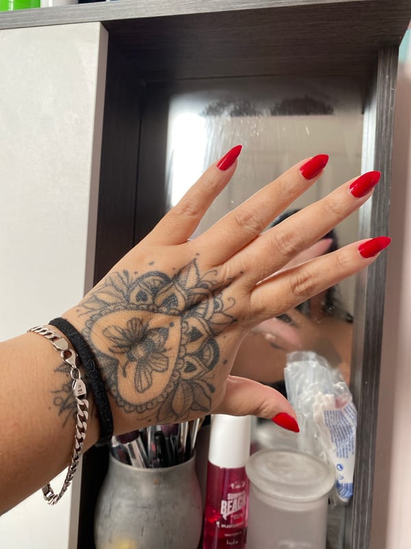 Hand with red nails and black tattoo photographed in Quito