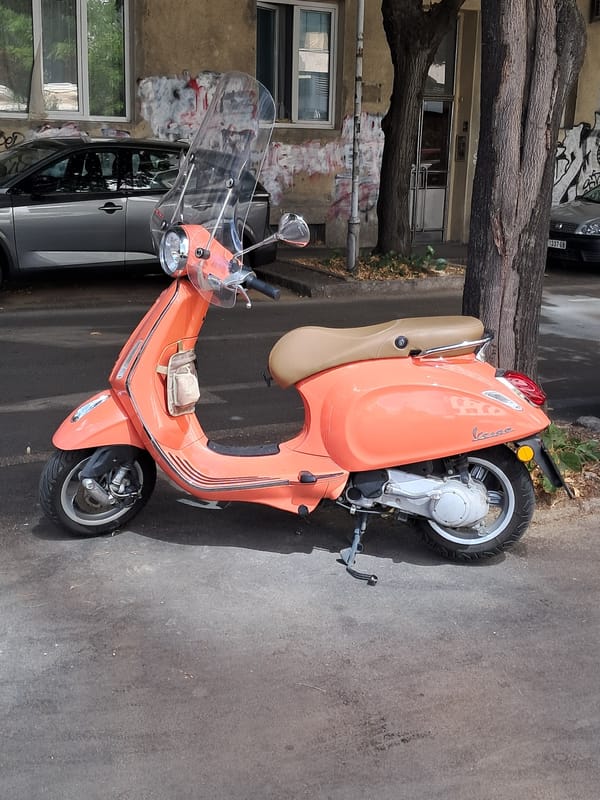 Orange Vespa parked outside a weathered Belgrade building