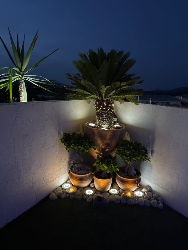 Vallada patio lights up at dusk around a jacuzzi and garden seating