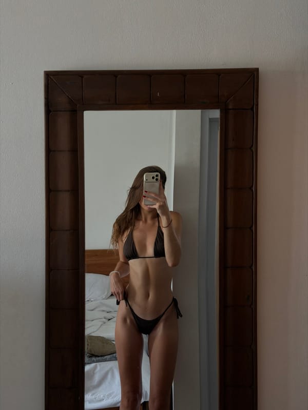 Woman takes mirror selfie in bikini in Tibubeneng room