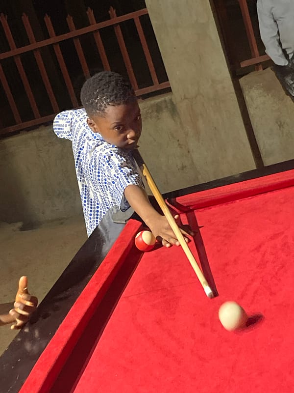 Boy plays outdoor billiards in Unguwar Gabas, Nigeria