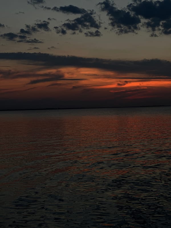 Sunset on a Kokshetau lake, boats and people on the water's edge