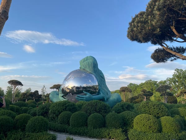 Park visitors document globe-embracing statue amid manicured gardens in Krasnodar