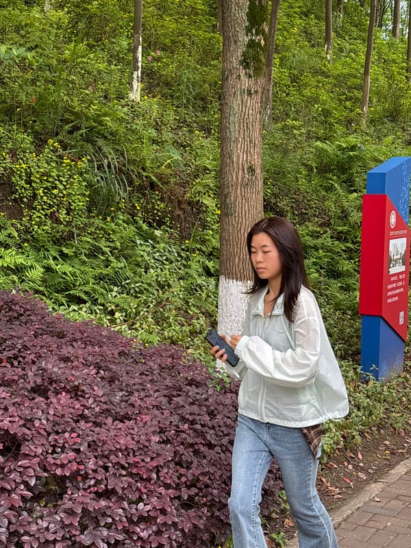 Woman rests against tree while using phone in Jiangjin