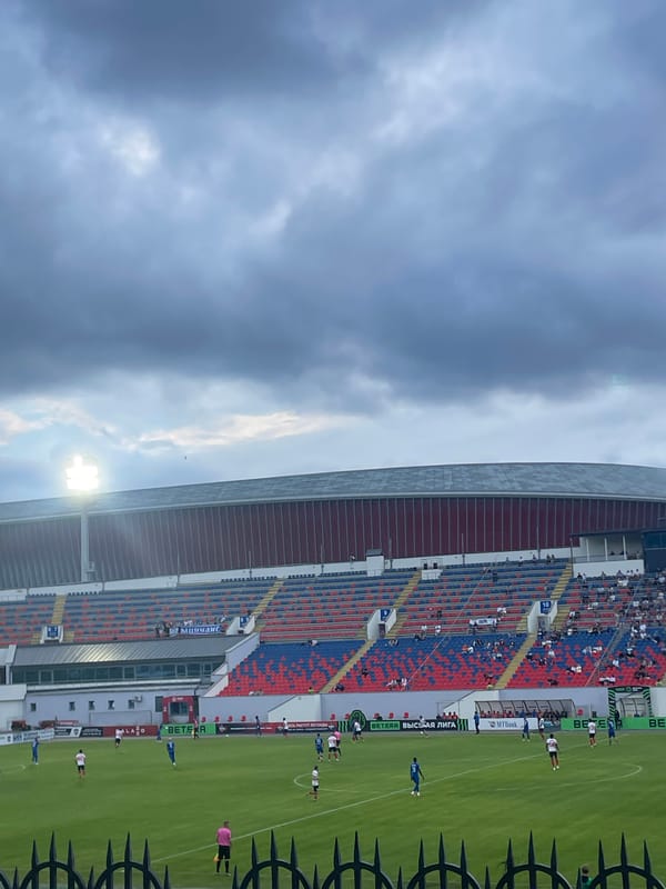 Live football match at a stadium with red and blue stands.