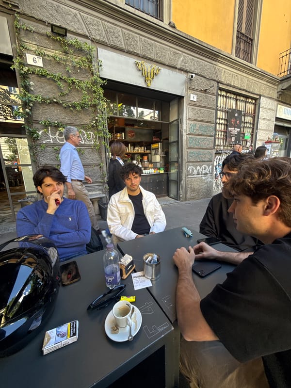 Four men gather at outdoor table near Milan shop