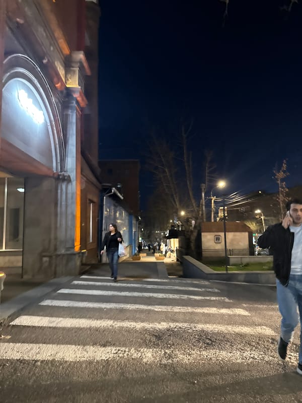 Pedestrian crosses street at night in Yerevan, Armenia