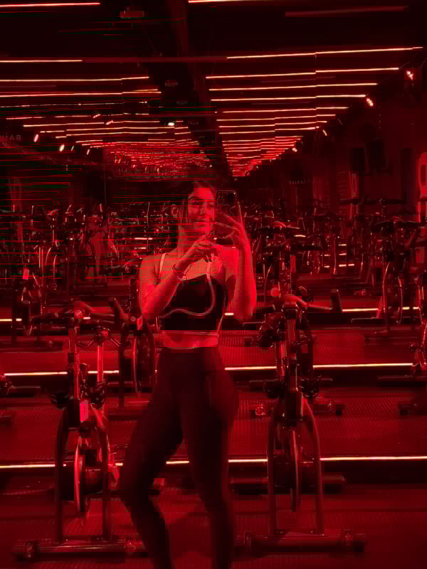 Woman photographed during cycling class in red-lit Puebla fitness studio