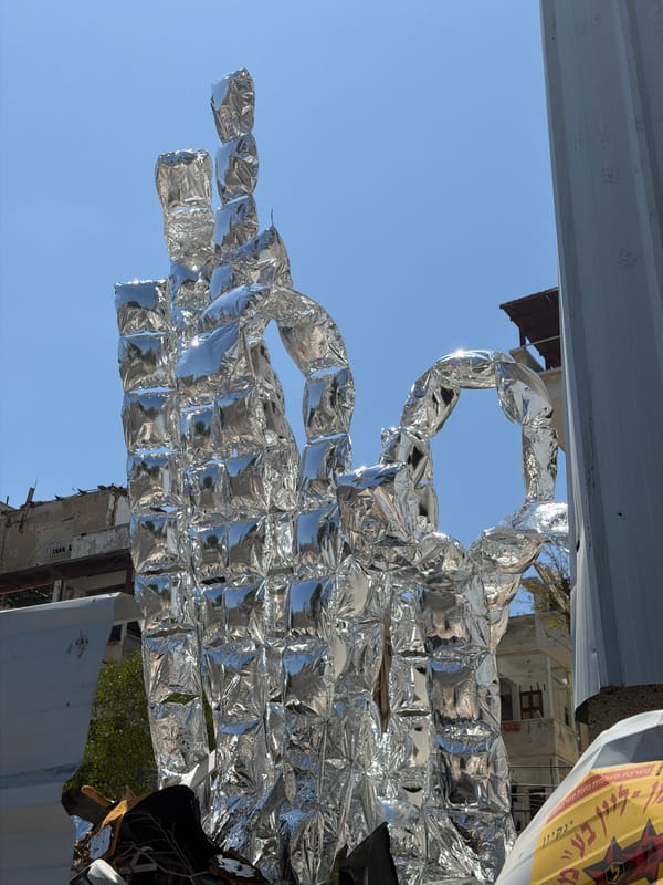 Reflective silver sculpture amid rubble on a Tel Aviv street