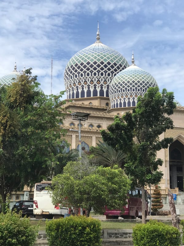 Mosque with twin domed architecture observed under partly cloudy skies