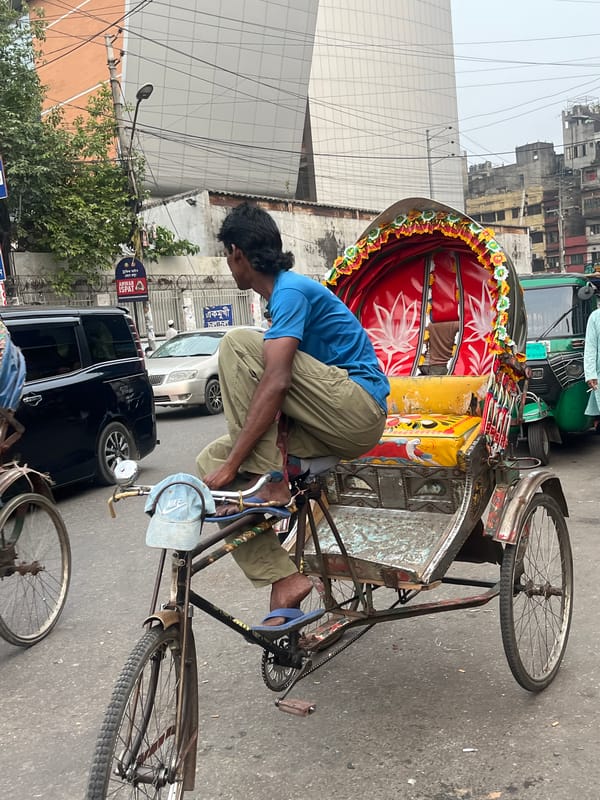 Decorated rickshaw navigates busy Dhaka streets amid typical urban activity