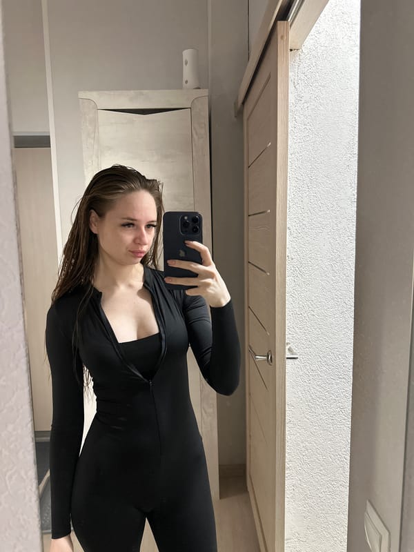Woman documents bathroom selfie session in black jumpsuit