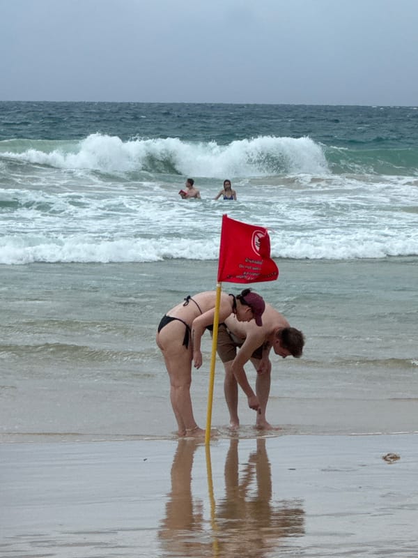 Karon Beach under warning flags, streets busy nearby