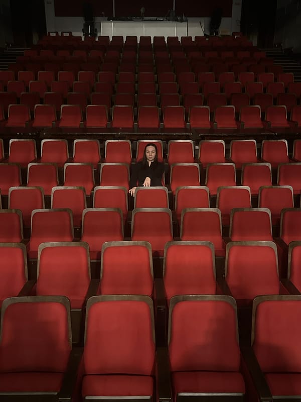 Empty red theater seats fill dimly lit auditorium