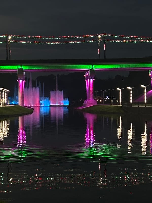 Bridge and fountains glow in purple and green at night