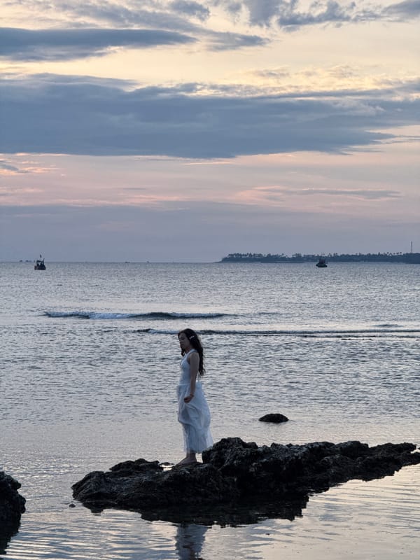 Dusk along Lý Sơn's volcanic shoreline, boats on the horizon