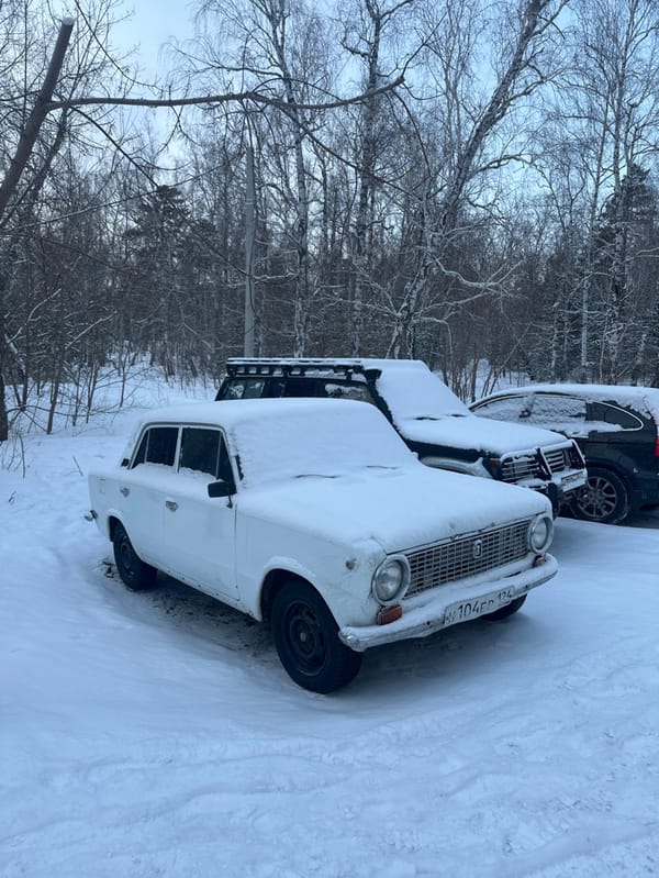 Vehicles parked in snowy forest area in Krasnoyarsk
