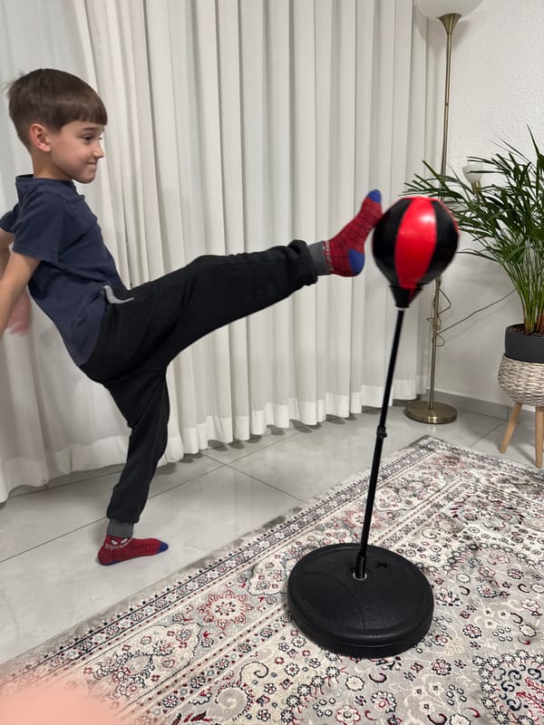 Child practices boxing with punching bag in Netanya home