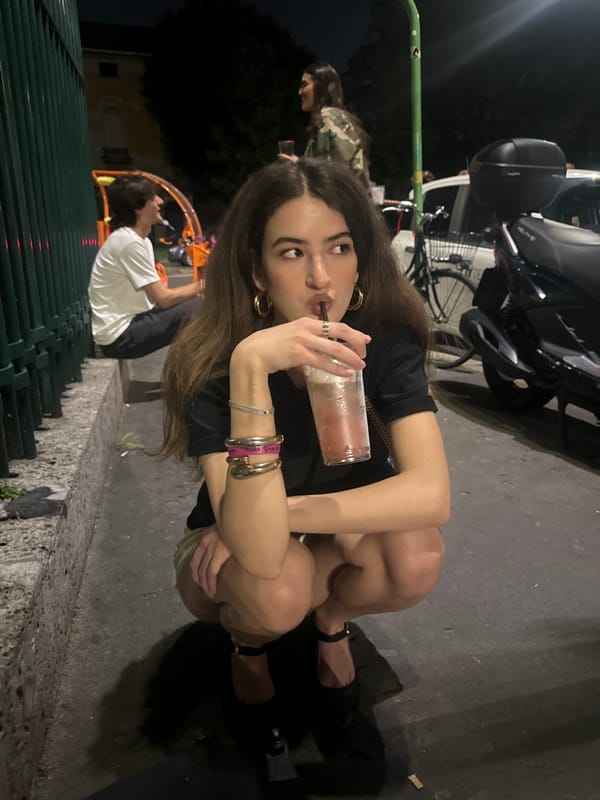 Woman with drink photographed on urban sidewalk Friday evening