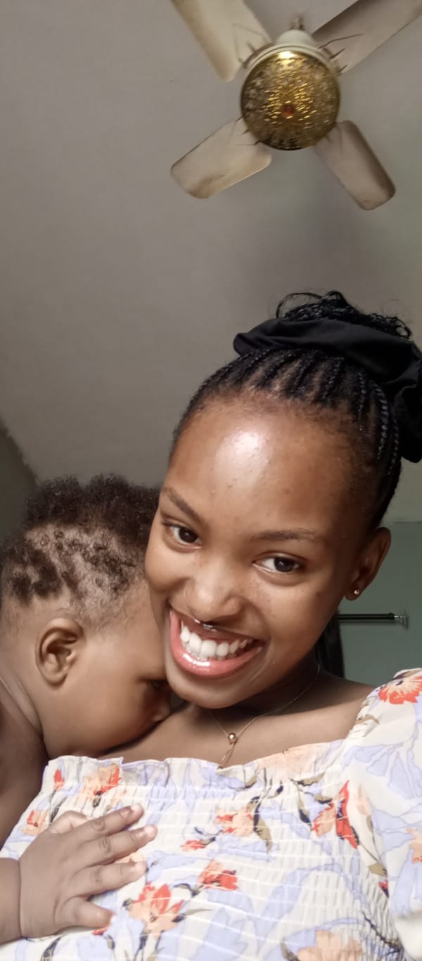 Woman with braided hair photographed holding child indoors