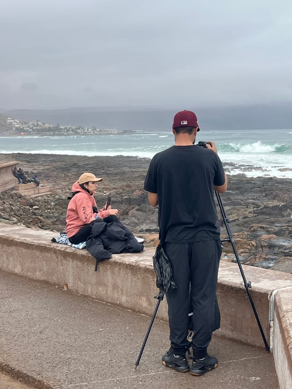 Surfers ride choppy break off Arica's rocky coast