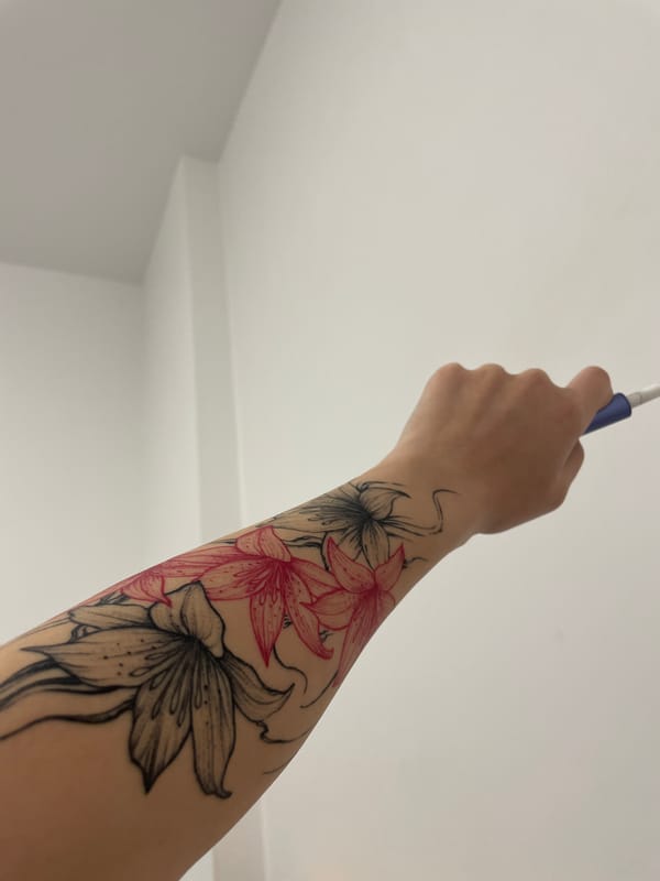 Person with floral tattoo holds electronic device in Sofia