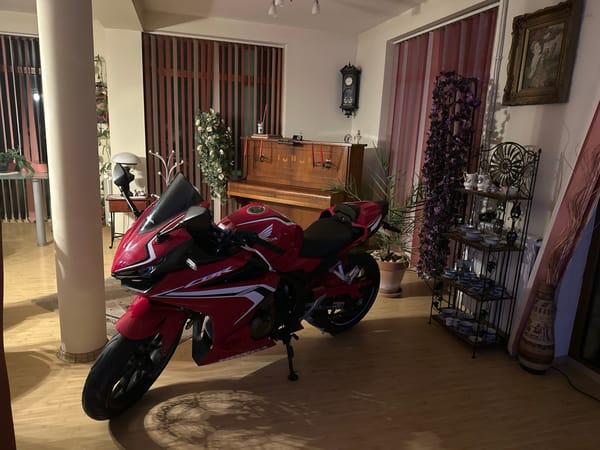 Red Honda motorcycle parked inside Bulgarian home near piano