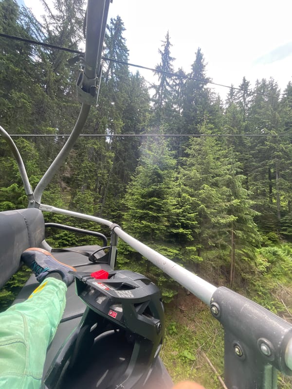 Chairlift ride up Chepelare mountain, bike helmet in tow