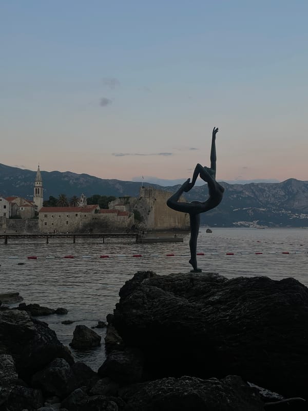 Tourist photographs iconic Budva ballerina statue and local architecture