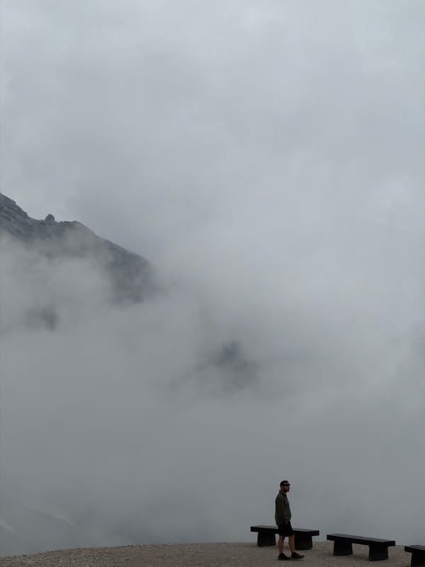 Hikers on a cloudy, snow-patched mountain trail in Wildermieming
