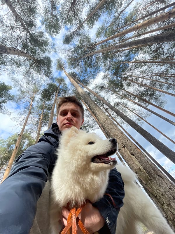 Person and white dog photographed in forest near water