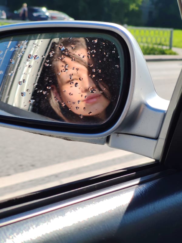Rain-dotted side mirror reflects a face in Yekaterinburg