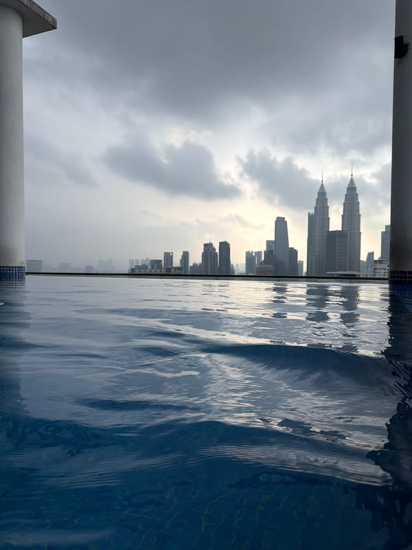 Woman enjoys rooftop pool overlooking Kuala Lumpur skyline
