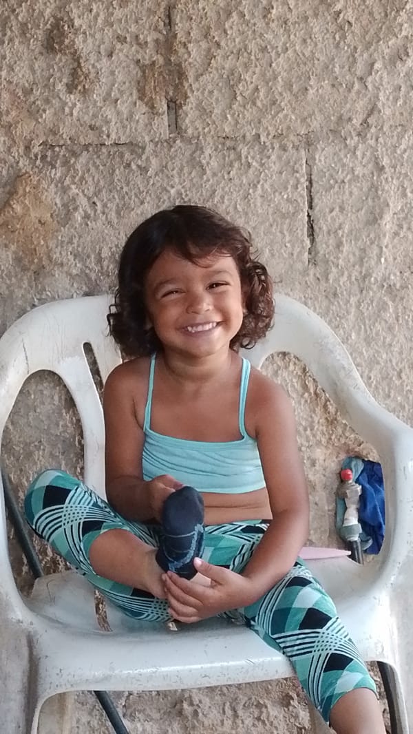 Young girl sits smiling with sock in Tinaquillo home