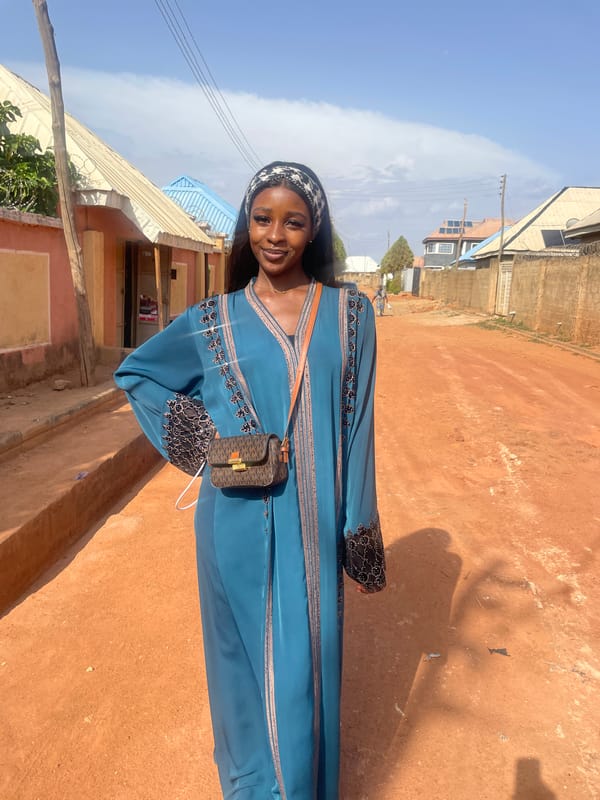 Woman uses smartphone on dirt road in Rido, Nigeria