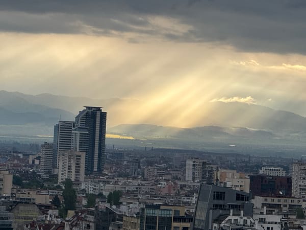Morning sunbeams pierce cloudy sky over dense urban cityscape